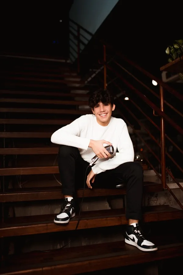 Arthur Endy sorrindo, sentado em uma escada
